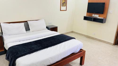 a bedroom with a bed with a tv on the wall at Hidden doors apartment in Ooty