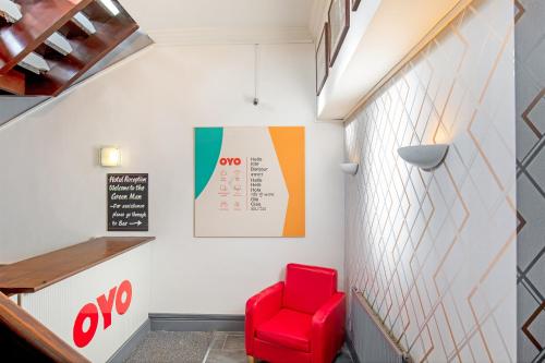 a red chair in a room with a wall at OYO The Green Man Pub And Hotel in London