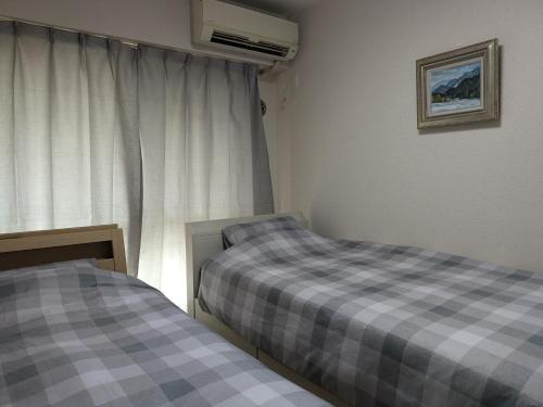 two twin beds in a room with a window at Colin Home Intimo Amigo in Tokyo