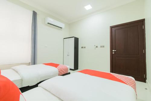 a bedroom with two beds and a door at Super OYO 106 Muscat Grand Hotel Apartment in Seeb