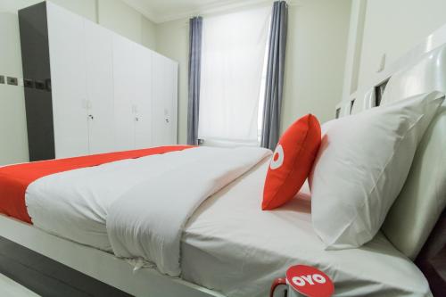 a bedroom with a bed with white sheets and red pillows at Super OYO 106 Muscat Grand Hotel Apartment in Seeb