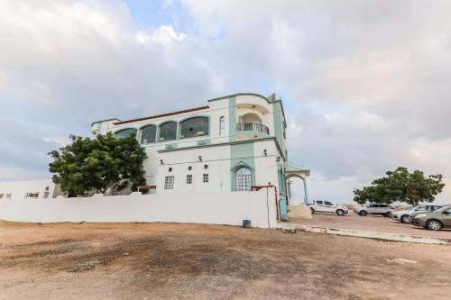 a building on a hill with cars parked in a parking lot at Super OYO 110 Ras Al Hadd Guest House in Al Ḩadd