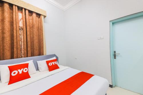 a bedroom with a bed with two red pillows at Super OYO 110 Ras Al Hadd Guest House in Al Ḩadd