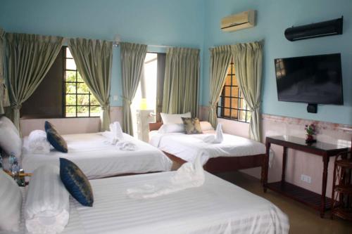 a hotel room with three beds and a flat screen tv at The Magic Sponge in Kampot