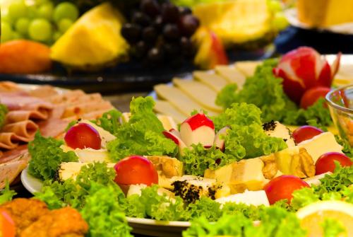 uma mesa coberta com pratos de alimentos com queijo e legumes em Superior Hotel Präsident em Munique
