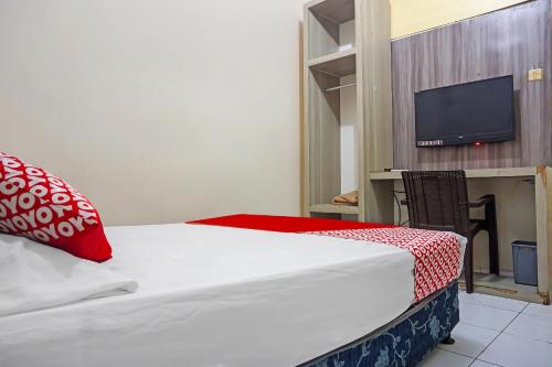 a bedroom with a bed with a red pillow and a tv at Hotel O Diamond Inn Makassar in Makassar