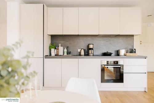 a white kitchen with white cabinets and appliances at 46 QM - Exklusiv & Top angebunden - Werse Loft by youpartments in Münster