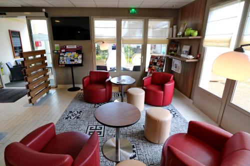 a waiting room with red chairs and a table at Campanile Albi Centre in Albi