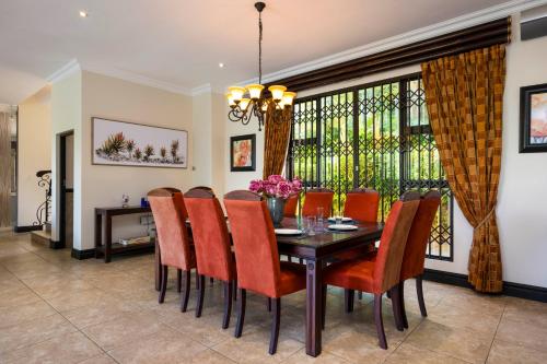 a dining room with a table and orange chairs at Marion Views in Ballito