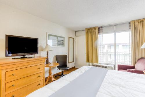 a hotel room with a bed and a flat screen tv at OYO Townhouse Owensboro West in Owensboro