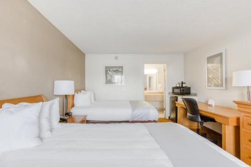 a hotel room with two beds and a desk at OYO Townhouse Owensboro West in Owensboro