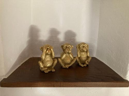 three gold figurines of monkeys sitting on a wooden shelf at Rustico Lucy in Gordola