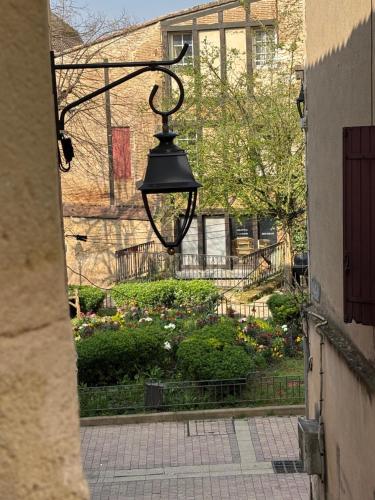 une lampe de rue suspendue à un bâtiment avec un jardin dans l'établissement Barrio Cyrano Appartement-Centre Historique, à Bergerac