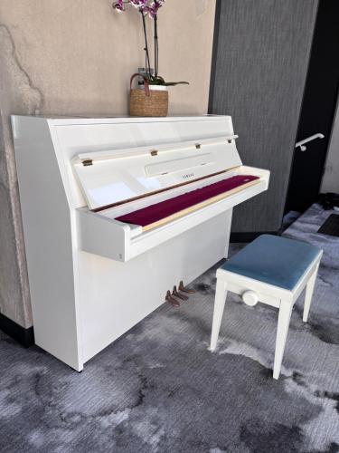 a white piano with a blue stool next to it at Hôtel égide in Espalion