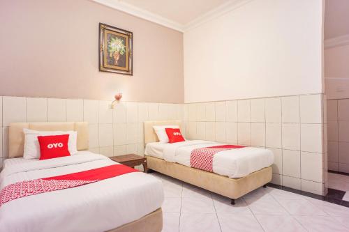 two beds in a room with red pillows at OYO 2180 Vina Vira Hotel in Lhokseumawe