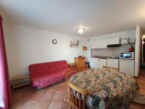 un salon avec une table et un canapé rouge dans l'établissement Appartement 3 pièces - 8 pers - 100m des pistes - Animaux & Parking inclus - FR-1-445-110, à Montgenèvre