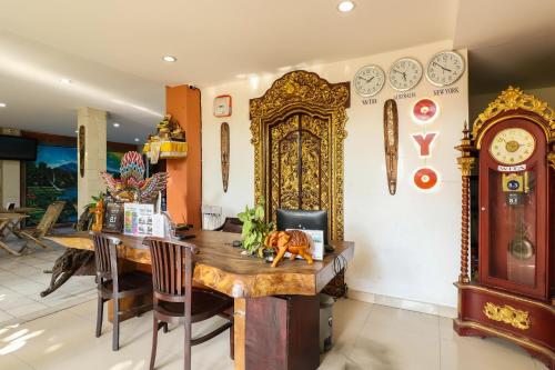 a dining room with a table and a clock on the wall at Capital O 1666 Grand Pudjawan Hotel Near Kuta Beach in Kuta