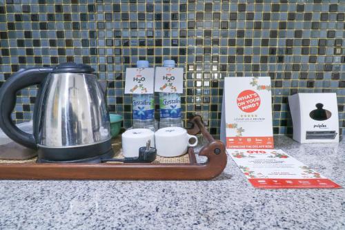 a tray with a tea kettle and cups on a counter at Capital O 1666 Grand Pudjawan Hotel Near Kuta Beach in Kuta