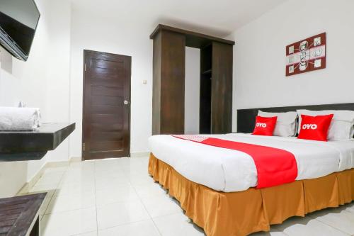 a bedroom with a large bed with red pillows at Capital O 1666 Grand Pudjawan Hotel Near Kuta Beach in Kuta