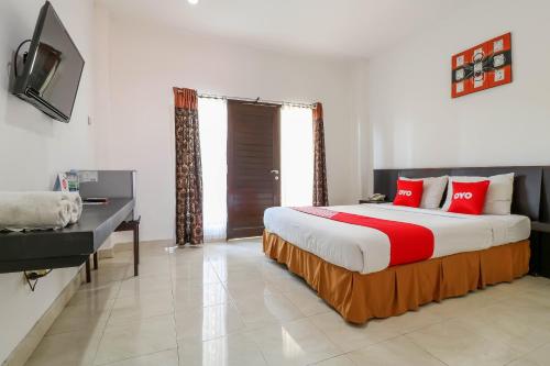 a bedroom with a large bed with red pillows at Capital O 1666 Grand Pudjawan Hotel Near Kuta Beach in Kuta