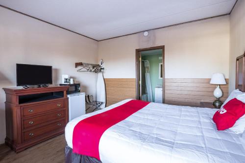 a bedroom with a large bed and a television at OYO Hotel Windmill Branson in Branson