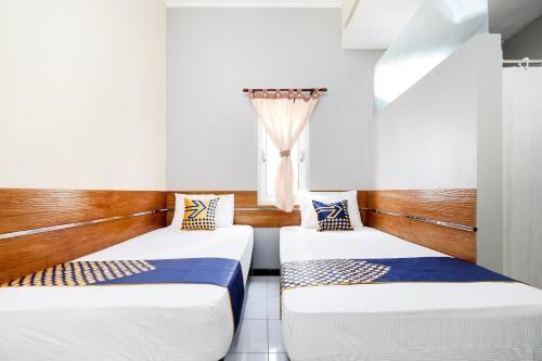 two beds in a room with a window at Hotel O Solo Point Guest House Syariah in Solo