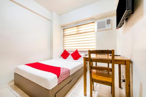 a bedroom with a bed and a desk and a window at OYO 474 Nizami Condotel in Manila