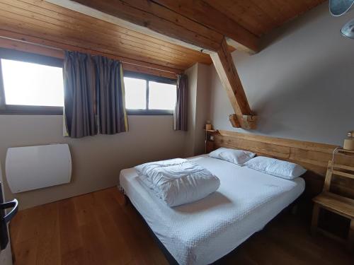 - une chambre avec un lit blanc et un plafond en bois dans l'établissement Chalet luxe refait à neuf, 50m des pistes, garage, terrasse, 125m², 8 pers, animaux acceptés - FR-1-445-192, à Montgenèvre