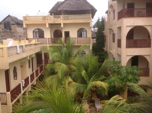 an apartment building with palm trees in front of it at Jannataan Hotel in Lamu