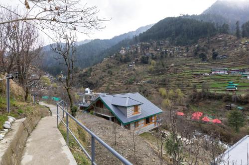 a house with a blue roof on a mountain at Eden Stay & Cafe in Jibhi