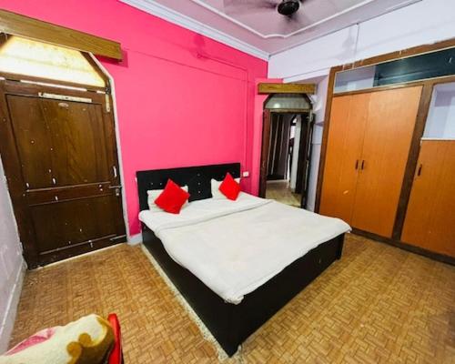 a bedroom with a bed with red pillows on it at Prayag Villa Inn in Allahābād