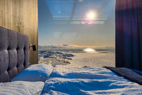 a window with a view of a beach with the sun at Mystic Light Lodge in Búðardalur