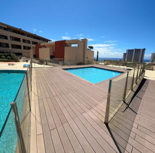 a swimming pool with a wooden deck next to a building at Bilbao House in Adeje