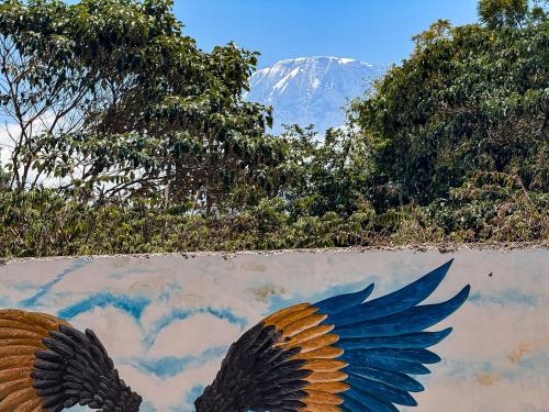 two wings painted on the side of a wall with a mountain at Karibu Africa Home in Moshi