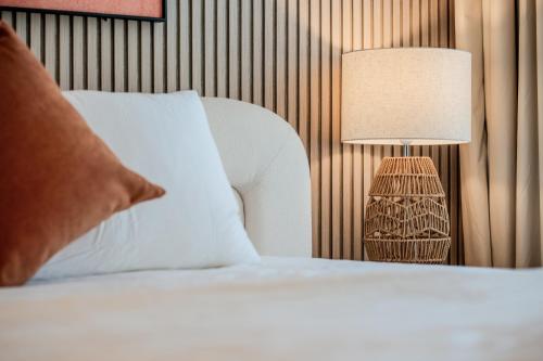 a bedroom with a white bed with a lamp at Fantastic Studio Royale Apartment At Al Mamsha in Sharjah Intl