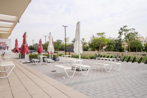 a patio with tables and white chairs and umbrellas at Fantastic Studio Royale Apartment At Al Mamsha in Sharjah Intl