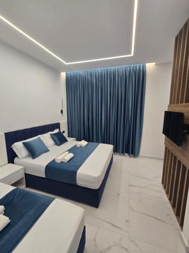 a bedroom with two beds and a blue curtain at Elite Inn in Vlorë