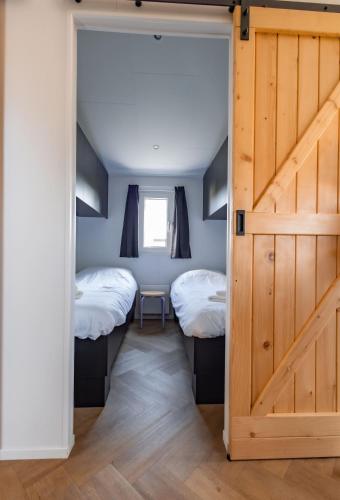 a bedroom with two beds and a sliding door at Nieuwe Luxe Lodge met Weidezicht - bij Nationaal park Drents-Friese Wold in Hoogersmilde