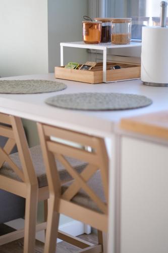 a kitchen counter with two stools and a table at Neringarent STUDIO-APARTAMENTAI in Juodkrantė