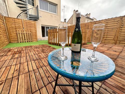 une bouteille de vin et deux verres à vin sur une table dans l'établissement Magic suite avec Balnéo, Sauna et terrasse, à Reims