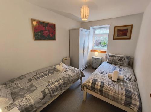a bedroom with two beds and a window at Smithy Cottage in Blairgowrie