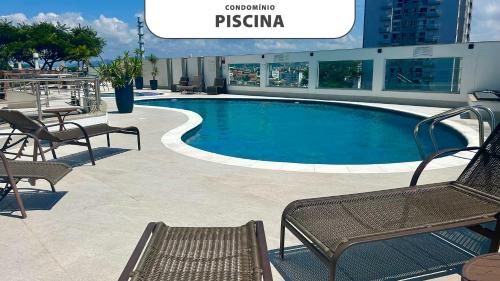 a swimming pool in a building with chairs and a table at Apto vista magnífica condomínio familiar Floripa in Florianópolis