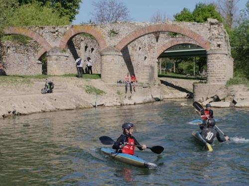 three people in kayaks on a river under a bridge at chambre privée Gournay sur Marne in Gournay-sur-Marne
