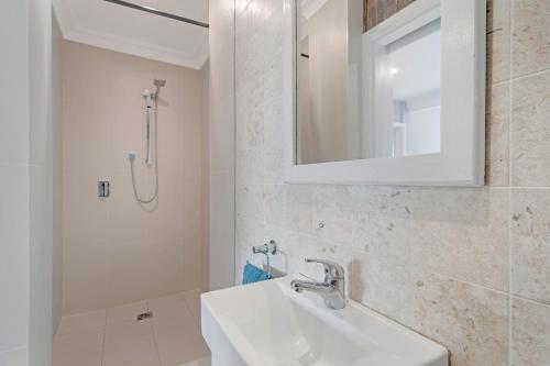 a white bathroom with a sink and a shower at Bush and Bay Haven in Bonnet Bay
