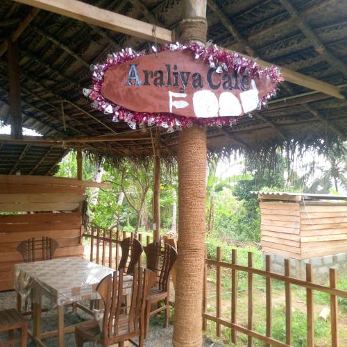 un restaurante con mesa, sillas y un cartel en Red Araliya Wooden House, en Dikwella