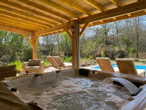 a hot tub in the middle of a patio with chairs at Gîtes & Spa de charme " Ploum" in Pouydesseaux