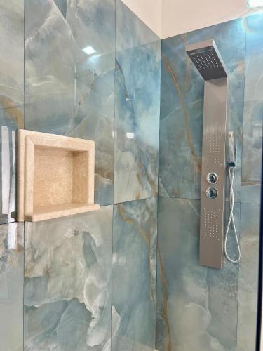 a shower with a glass door with a stone wall at Villa Scirocco in Cala Liberotto