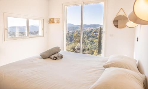 une chambre avec un grand lit blanc avec une grande fenêtre dans l'établissement Magnifique Villa piscine chauffée, climatisée, vue mer sur les Issambres, aux Issambres