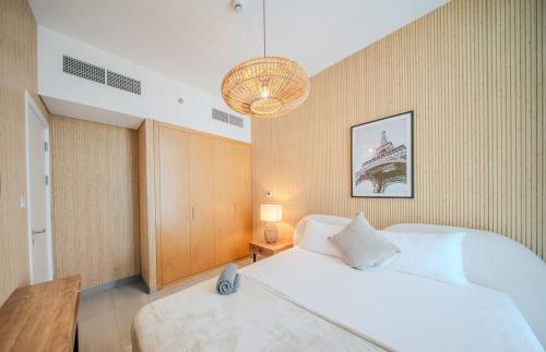 a bedroom with a large white bed and a chandelier at 1BR Exclusive Apartment - Charisma in Sharjah Intl