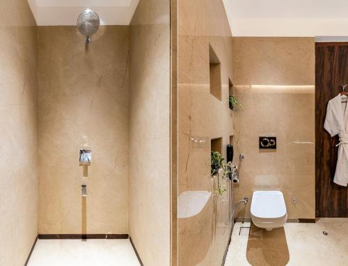 a bathroom with a toilet and a glass shower at Sajjan Bagh Resort Kumbhalgarh in Kumbhalgarh
